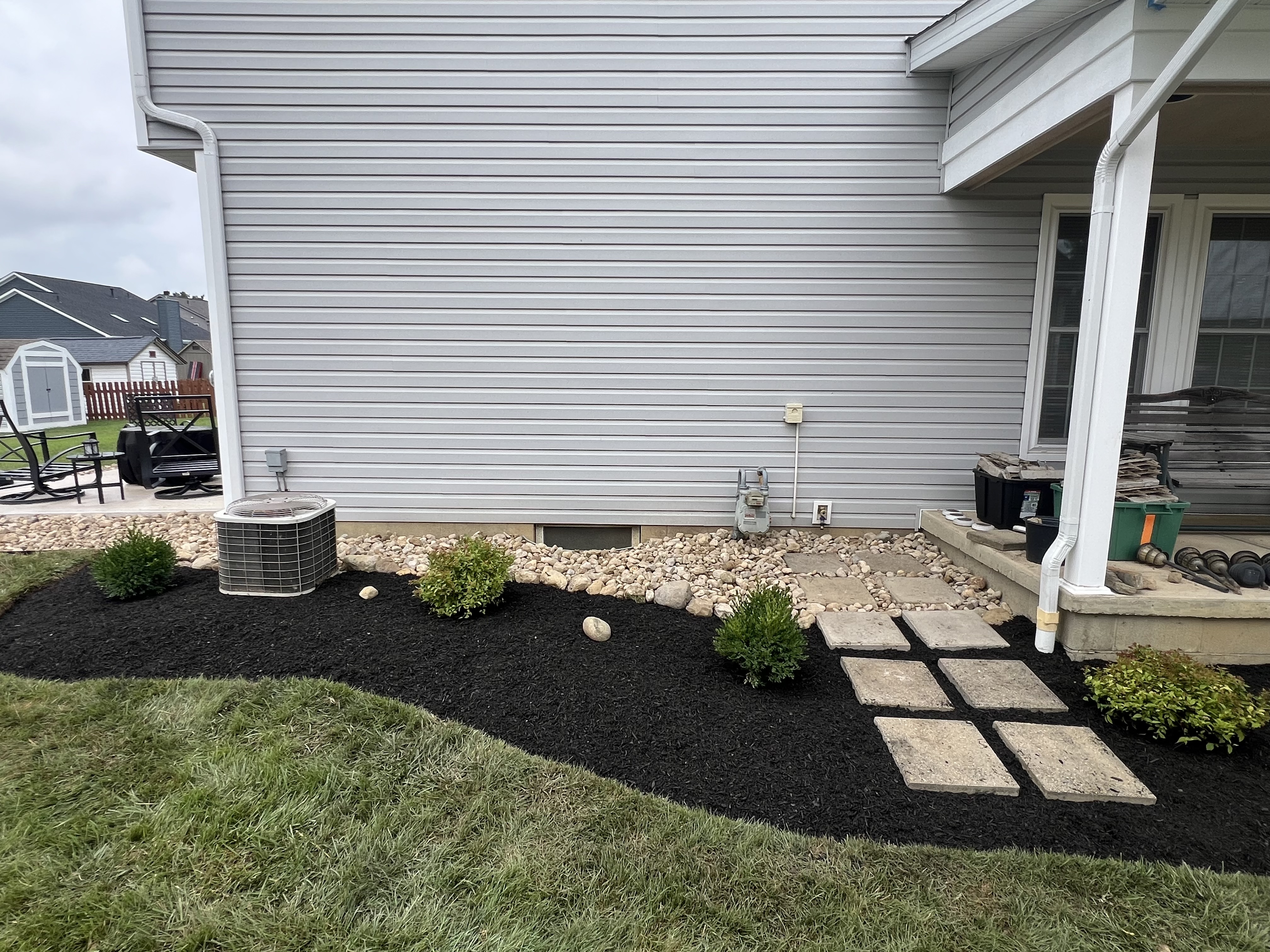 Backyard patio bordered by river rock after a full landscape remodel in Plain City, Ohio