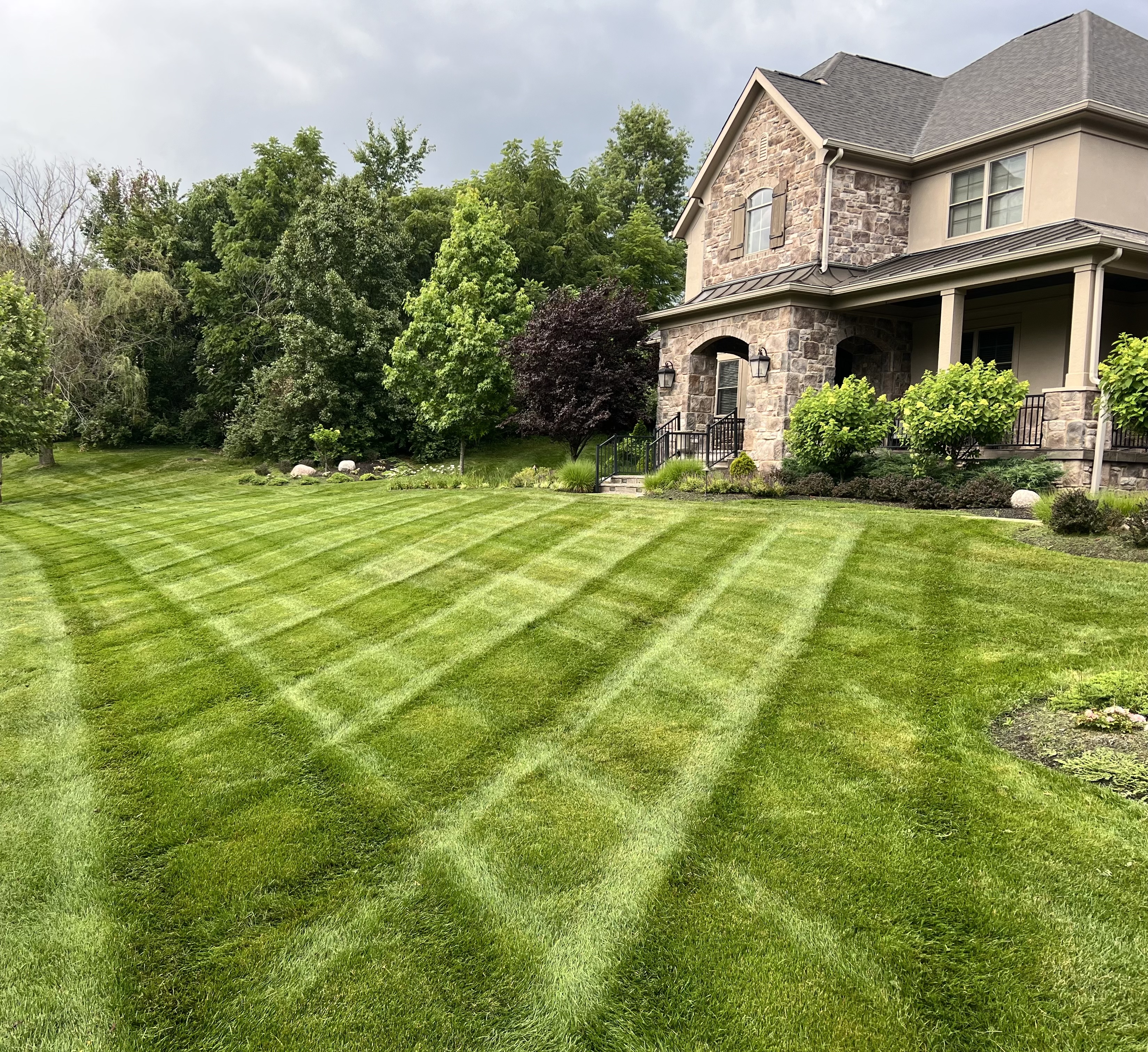 Freshly mowed lawn with mowing stripes in front of a stone-front home in Central Ohio