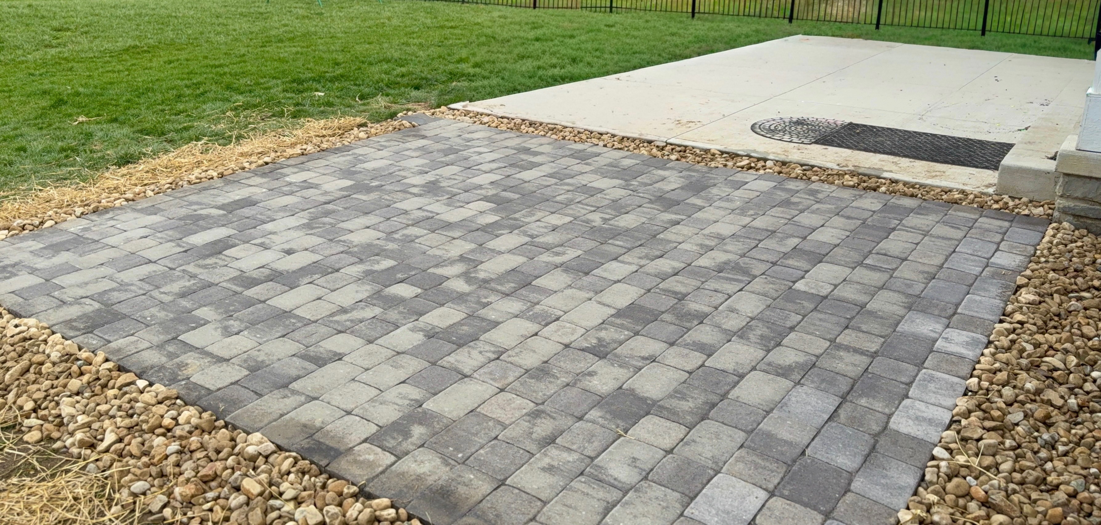 Newly installed paver patio in a fenced backyard